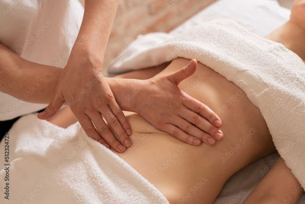 relaxing massage and body shaping massage, lymphatic drainage, manual and aesthetic procedures, hands massaging belly in the spa