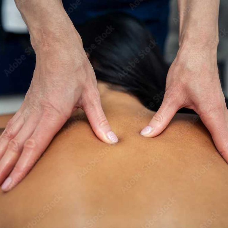 Attractive girl is relaxing on classic massage procedure in spa. Manual therapy. Masseur is doing back massage