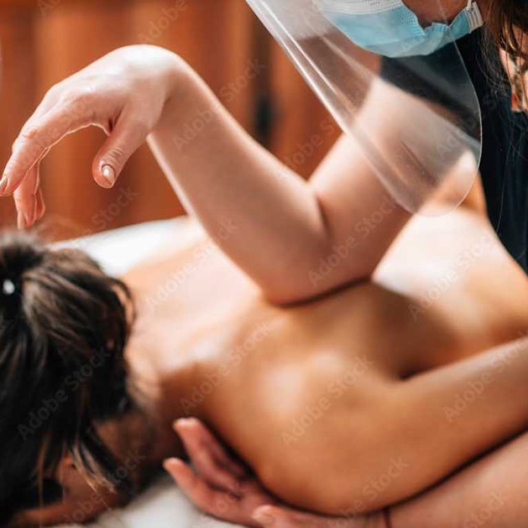 Lomilomi Practitioner wearing a Protective Mask, Giving Back Massage at a Wellness Center